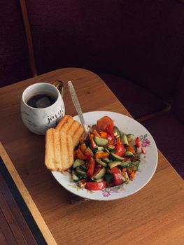 Vibrant vegetable salad with toast and coffee on a wooden table, perfect breakfast.