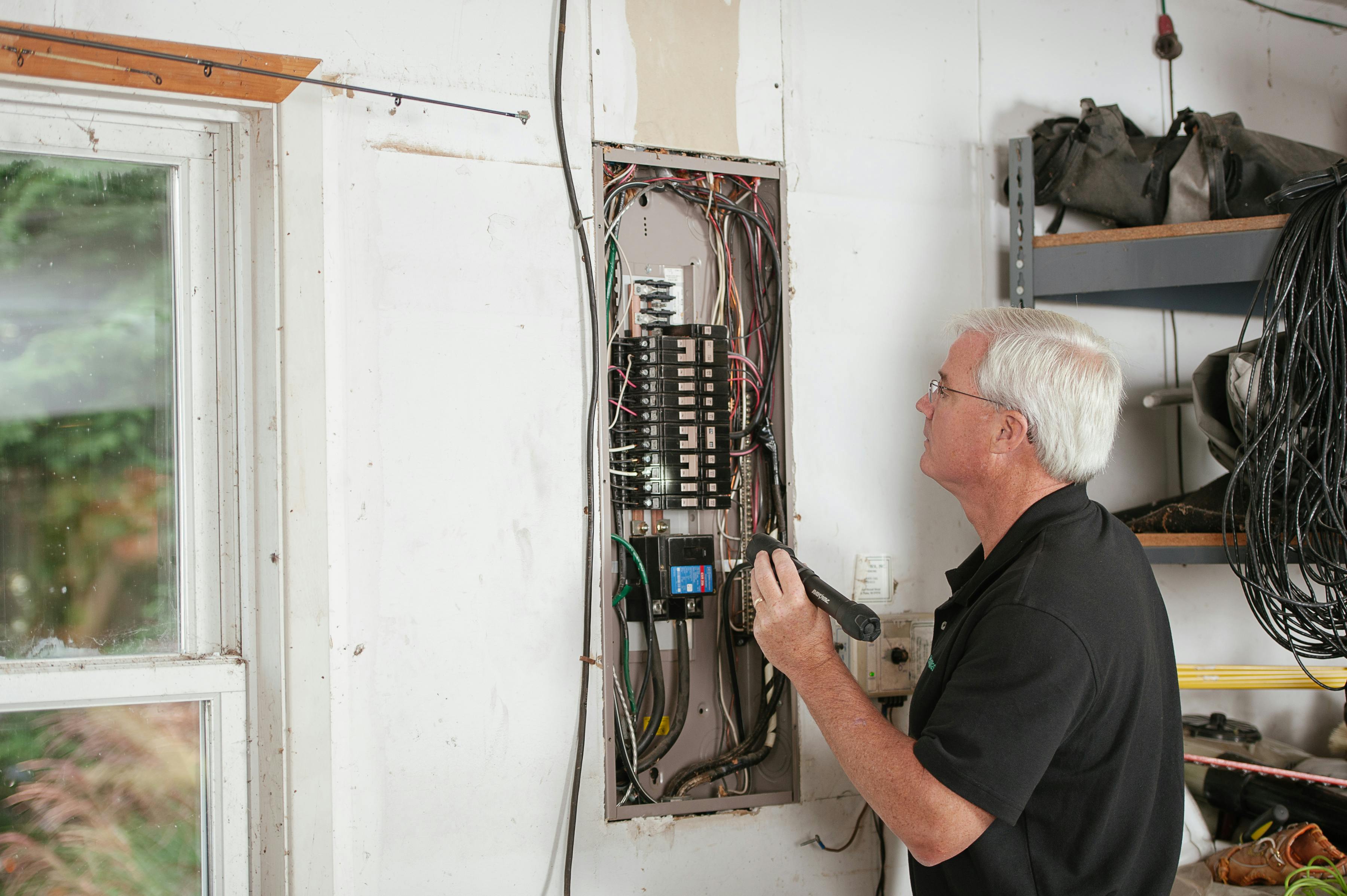 Image Name Licensed electrician installing a main breaker panel in a modern home