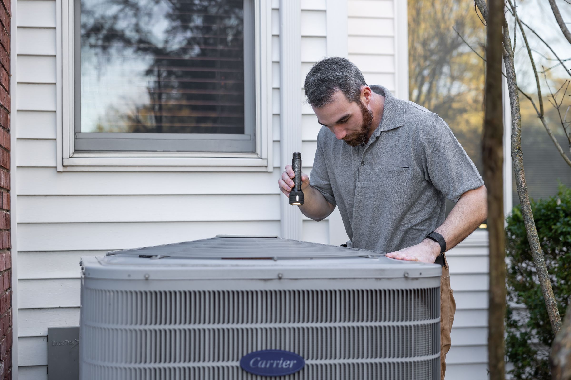 HVAC technician servicing a residential air conditioner condenser unit