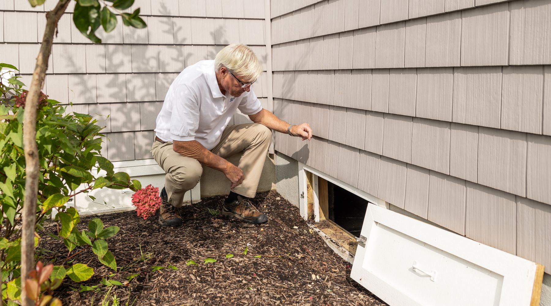 Inspector checking a crawl space entrance on a Charlotte home