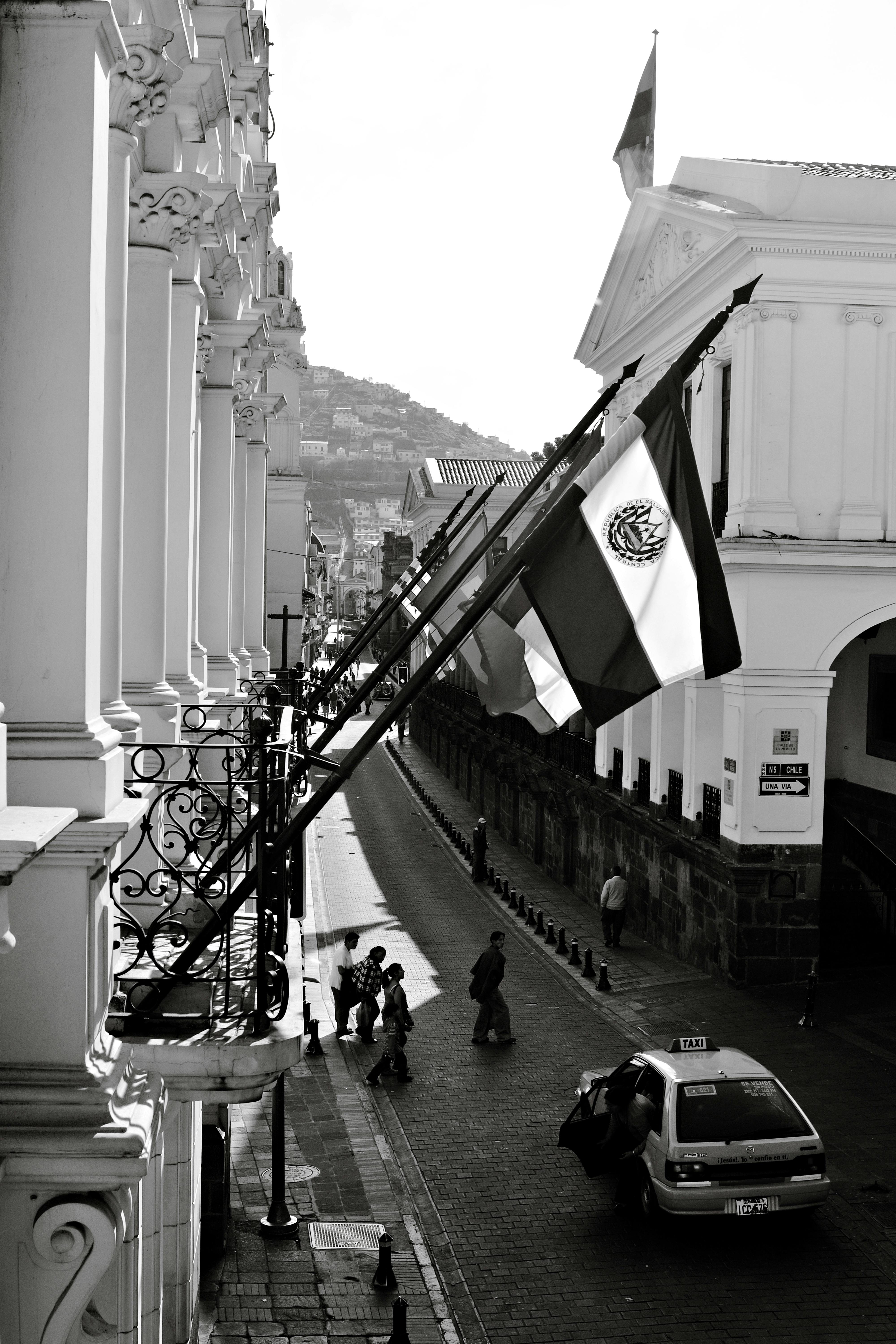 Ücretsiz Sömürge mimarisi ve bayraklarının sergilendiği Quito'nun siyah beyaz sokak görünümü. Stok Fotoğraflar