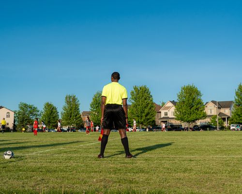 Free Referee oversees a soccer match on a sunny day in a suburban neighborhood. Stock Photo