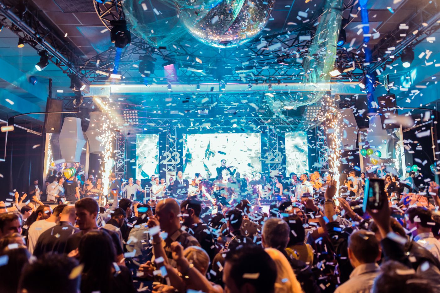 Silhouetted crowd dancing under neon lights and confetti