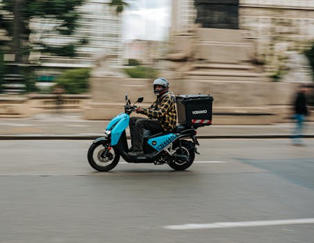 A delivery person rides a scooter swiftly through São Paulo's bustling streets.