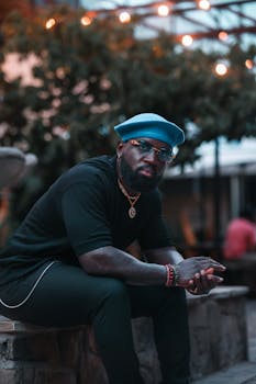 Portrait of a fashionable man in the evening wearing a beret and jewelry amidst urban lights in Corpus Christi.
