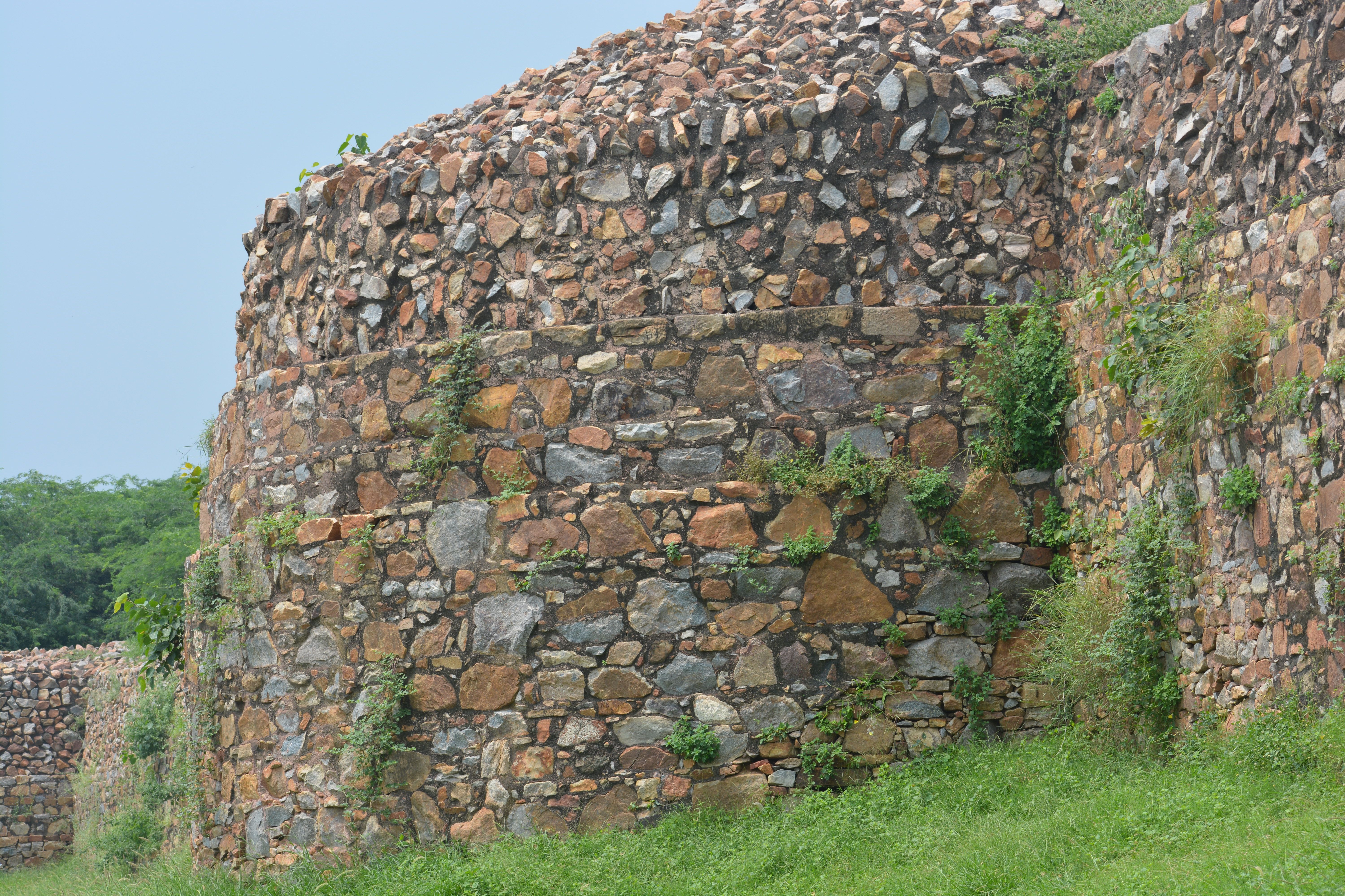 Ruined stone bastions of Tughlaqabad Fort rising above scrub in south Delhi at golden hour