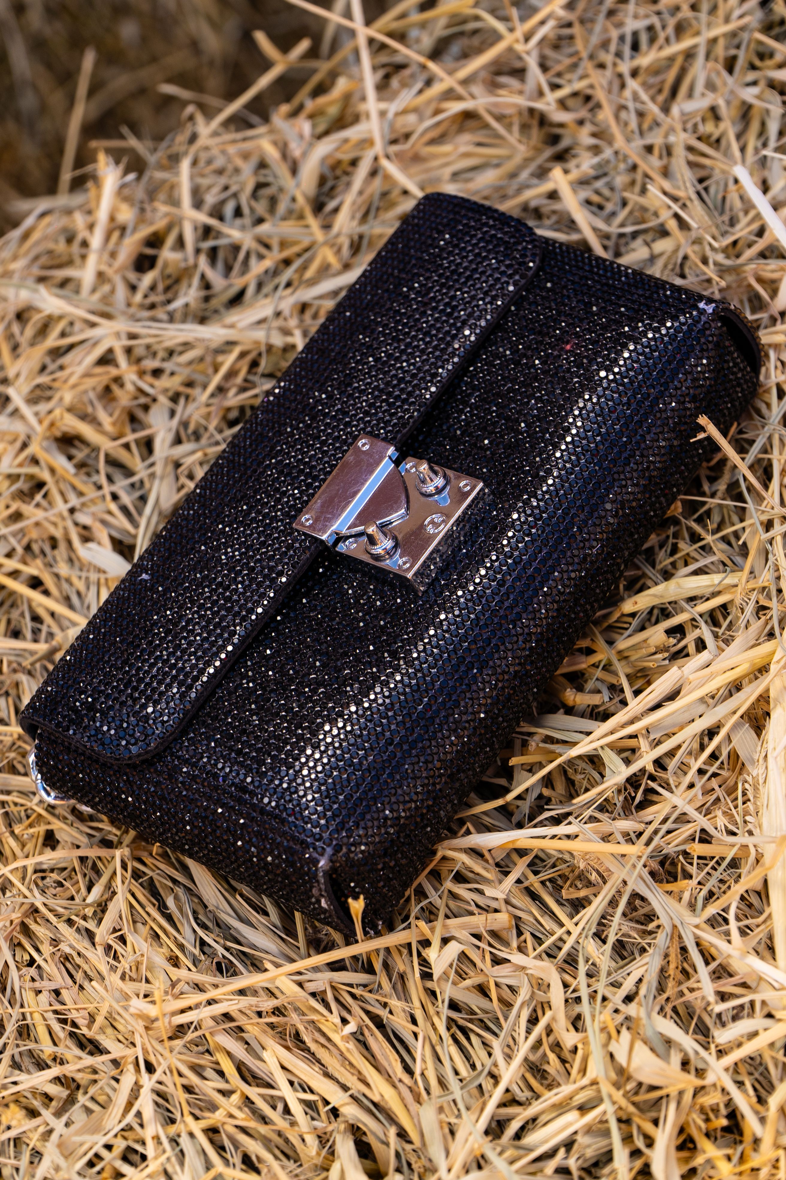 Bolsa clutch preta estilosa feita de palha, oferecendo um visual rústico e ao mesmo tempo chique.