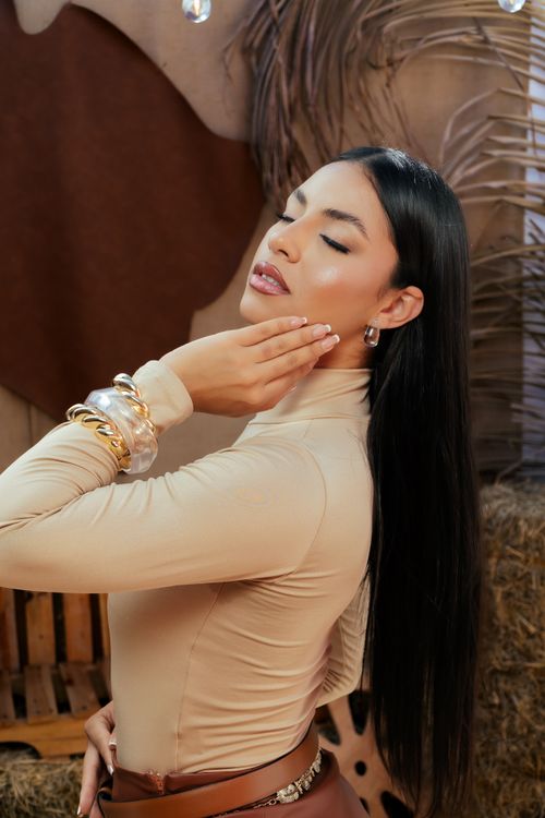 Free Fashionable woman in a beige top posing gracefully with elegant jewelry. Stock Photo