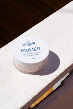 Catharine Hill primer jar on a sunlit wooden surface, emphasizing beauty and skincare.