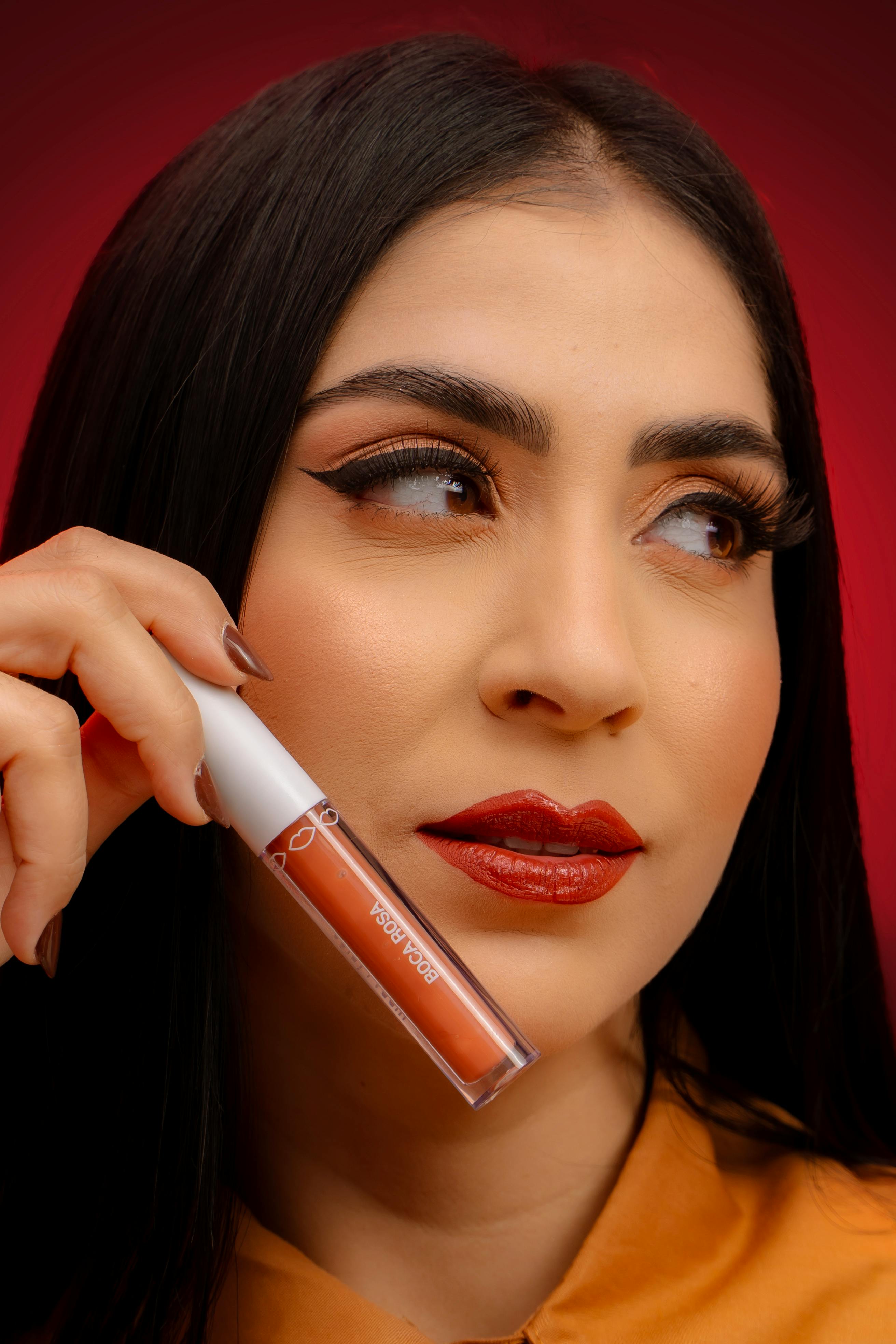 免費 一位女士的特寫肖像，以紅色背景展示唇彩。 圖庫相片