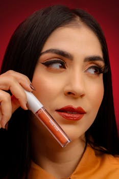 Close-up portrait of a woman showcasing lip gloss with a red backdrop.