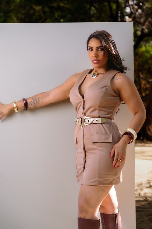 Free Stylish woman in beige dress posing confidently outdoors with sunlight casting soft shadows. Stock Photo
