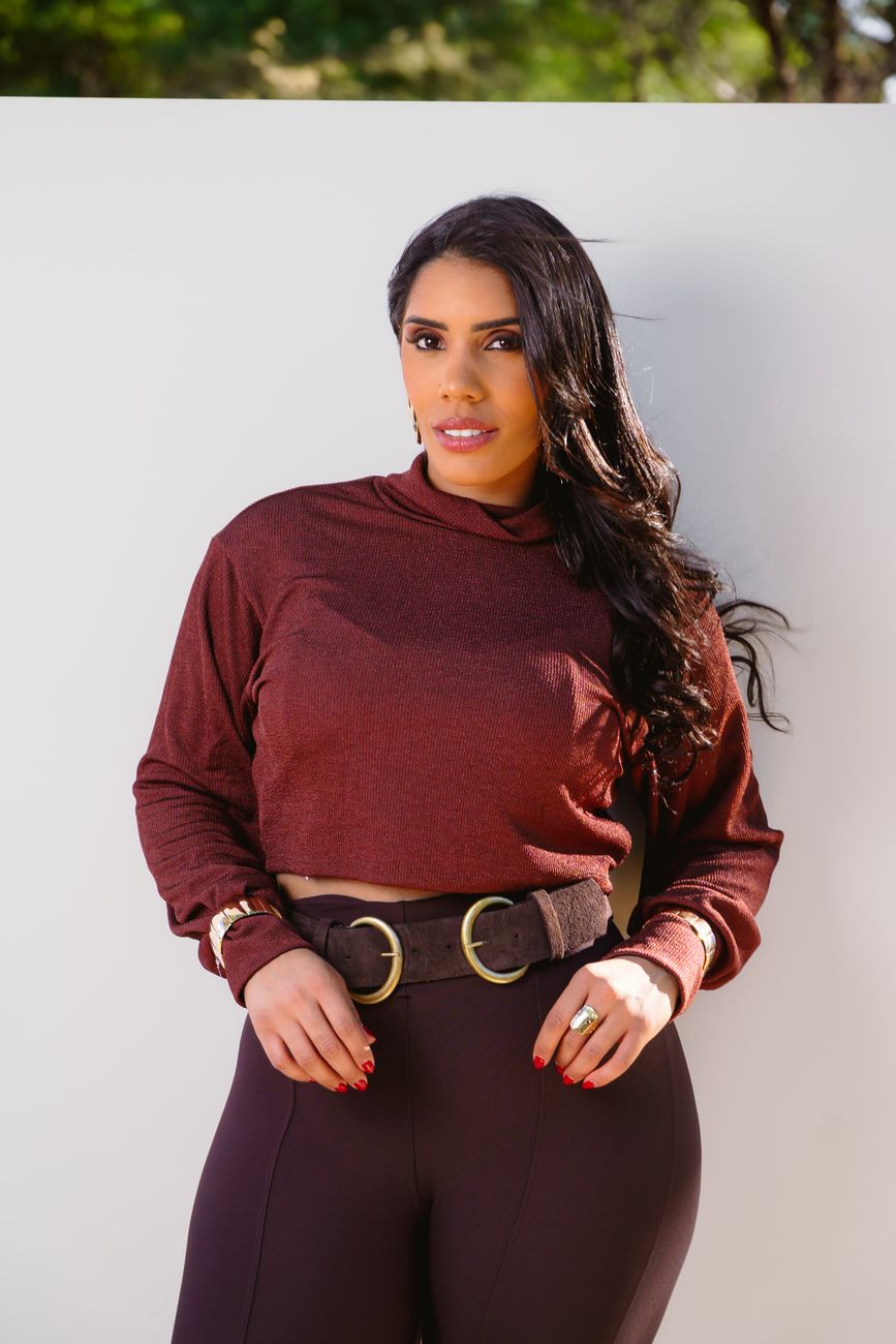 Retrato de uma mulher confiante vestindo um traje burdeos estiloso ao ar livre com luz natural.