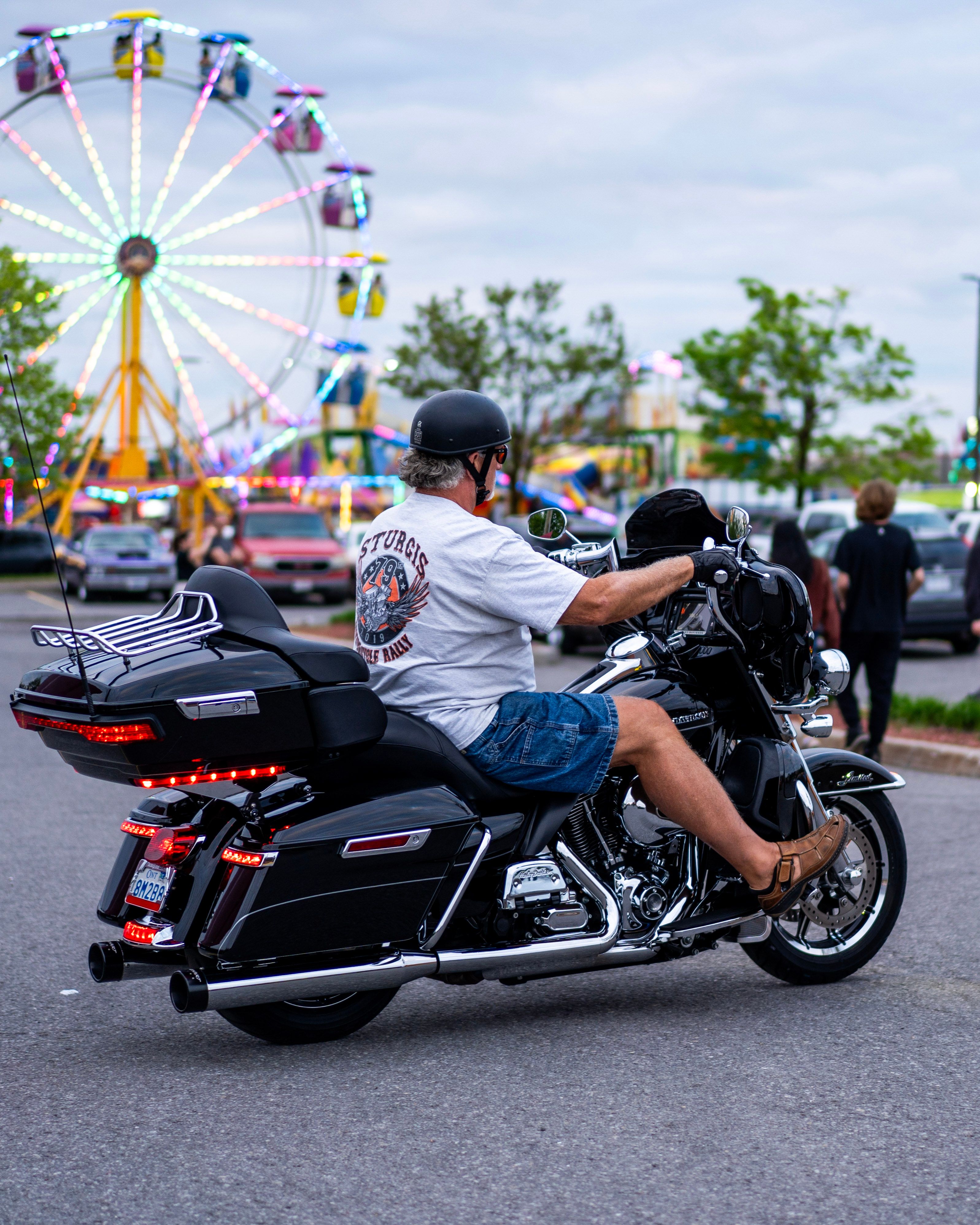 Motorcycle Rider at Carnival with Ferris Wheel · Free Stock Photo