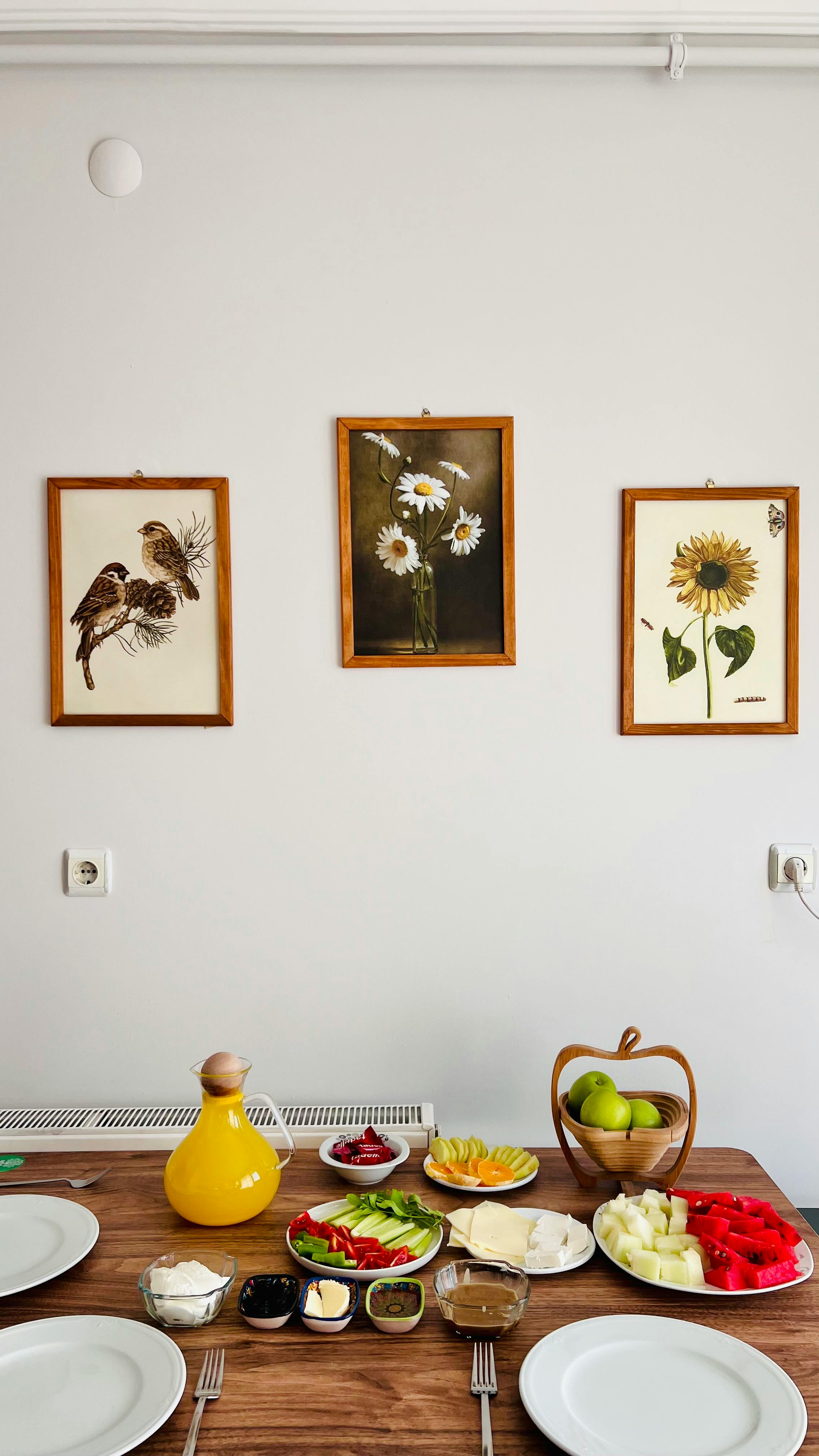 A vibrant Turkish breakfast table with fruits and artwork on a wall.