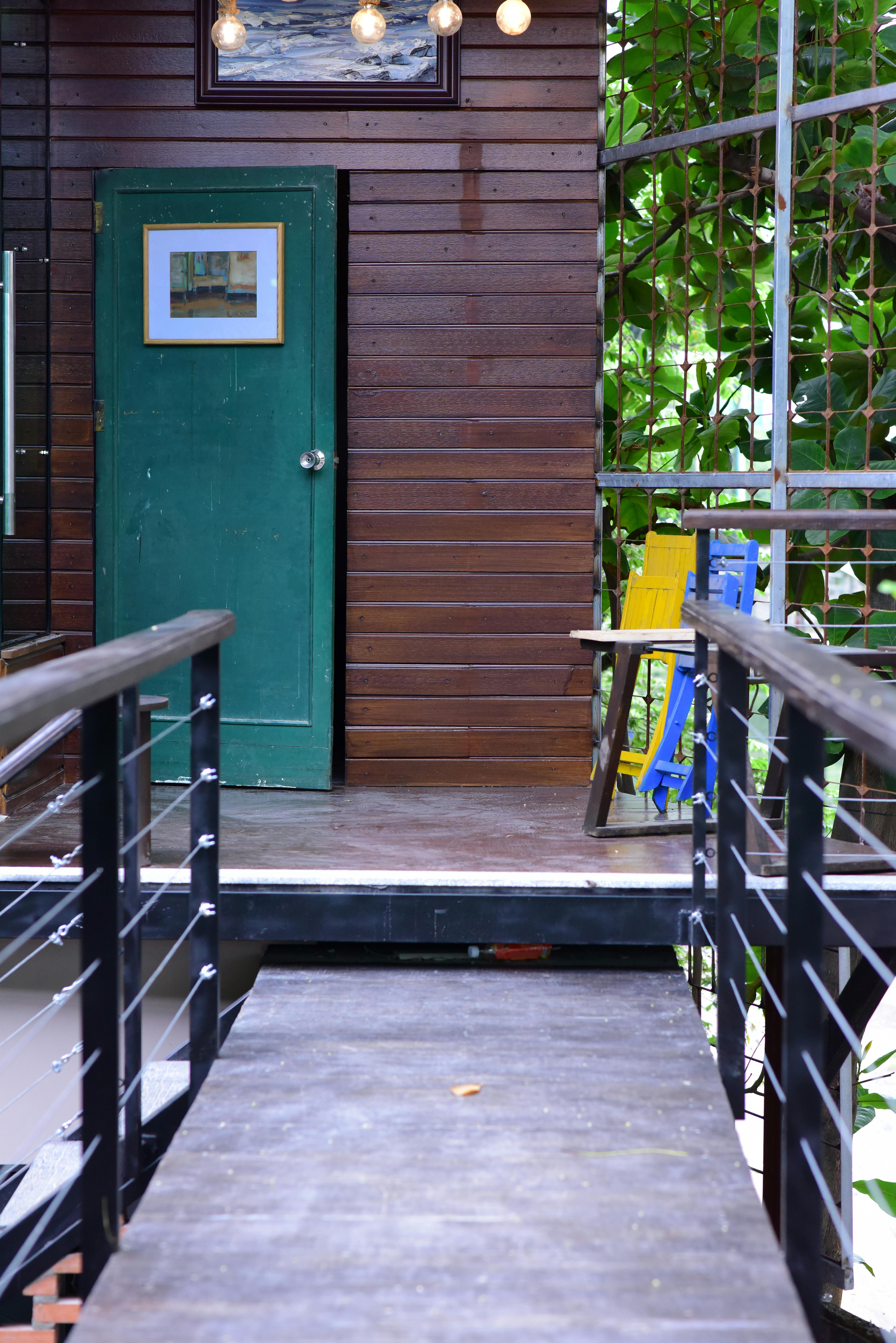 Wooden patio with a colorful chair and green door, creating an inviting outdoor space.