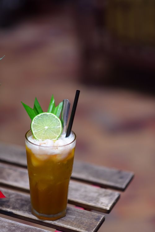 Free Close-up of a tropical cocktail with lime and green garnish on a rustic wooden table. Stock Photo