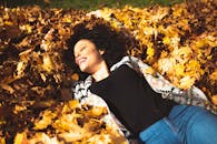 一个女人快乐地躺在黄叶堆里，享受着秋日的阳光