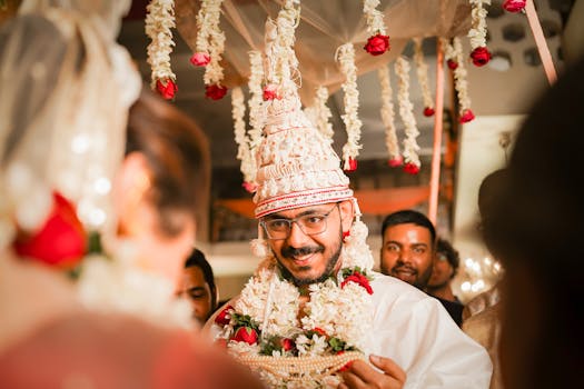 Groom smiling during a traditional Indian wedding ceremony, adorned with floral garlands.