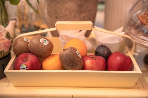 Free A charming arrangement of fruits including apples, kiwis, and oranges in a wooden basket. Stock Photo