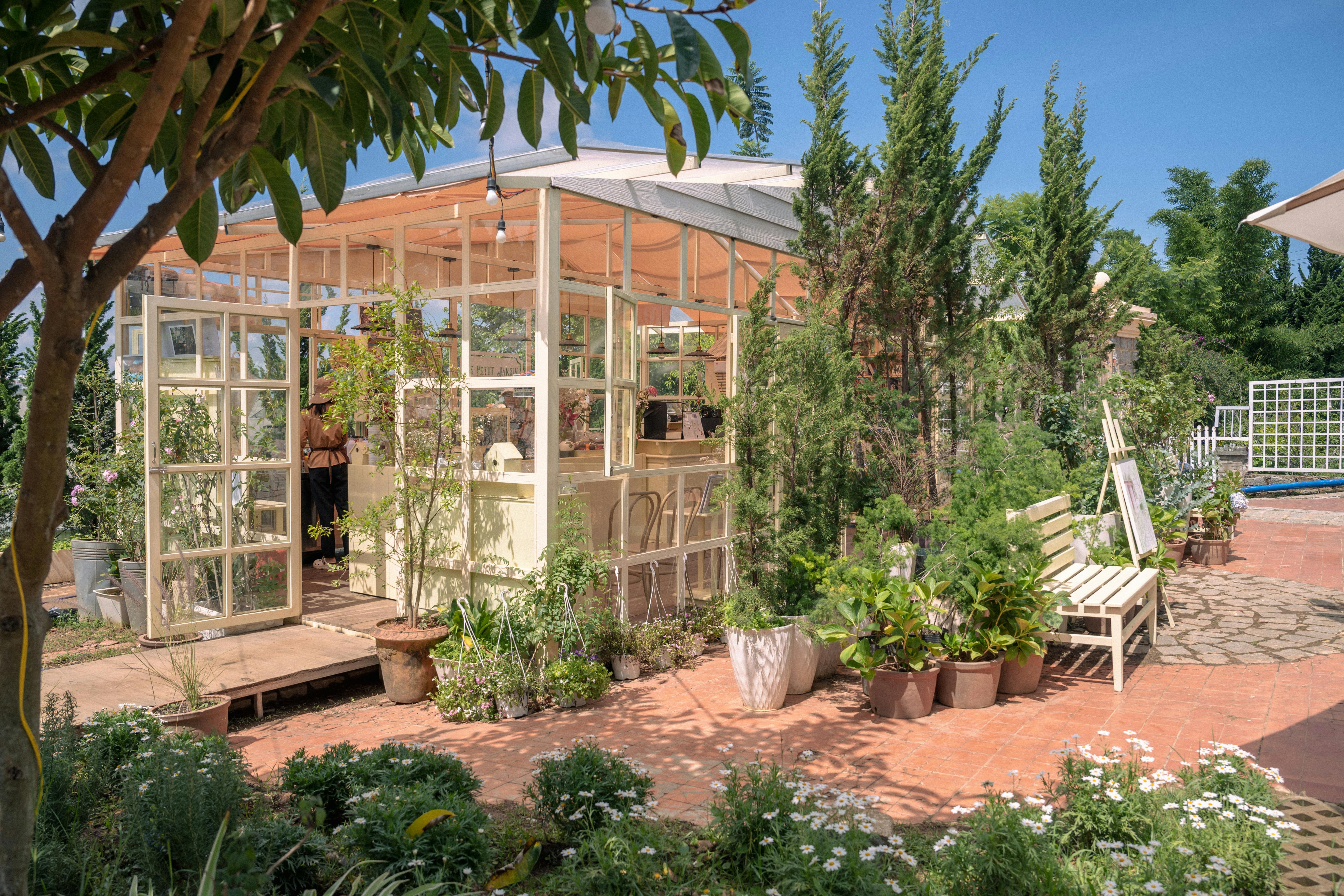 Une serre ensoleillée entourée d'une verdure luxuriante et de fleurs en fleurs dans un jardin paisible.