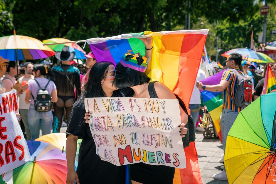 Desfile del orgullo colorido que captura momentos alegres y solidaridad LGBTQ+ en un entorno soleado al aire libre.