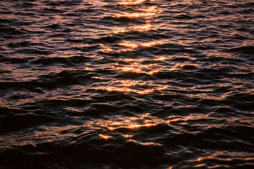 Free Golden sunset reflections on the rippling water surface in Hanoi, Vietnam. Stock Photo