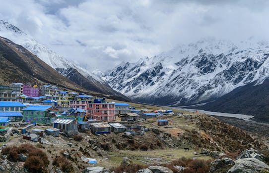Colorful alpine village in Sikkim, India with snowy mountains backdrop.