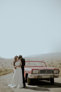 Elegant couple enjoying a moment by a classic car in Udaipur, India.