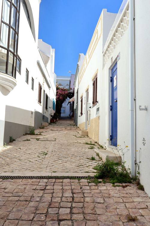 Free Explore a quiet Mediterranean alleyway with whitewashed walls and iconic blue door. Stock Photo