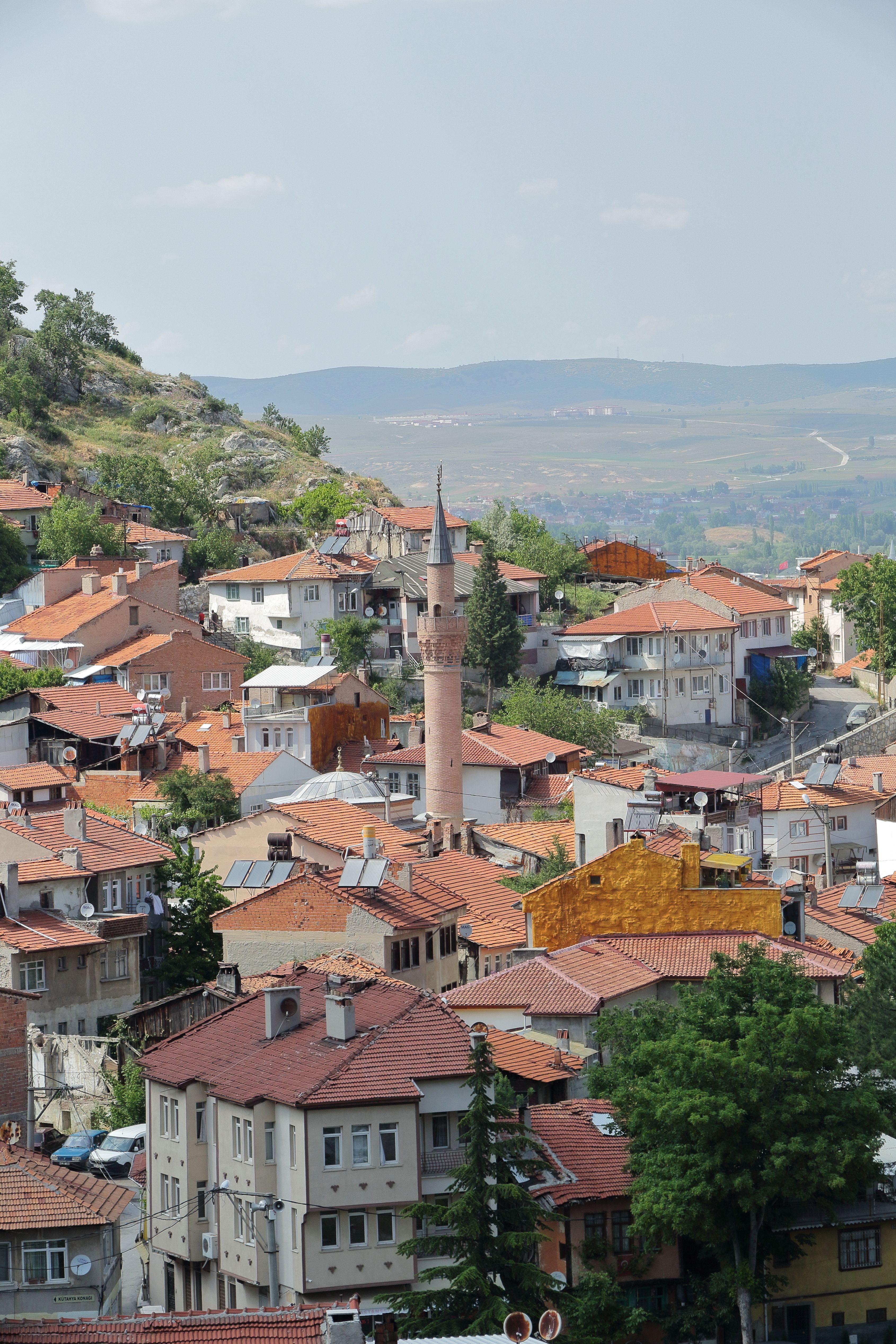 A scenic view of a Turkish town featuring a central minaret and surrounding landscape.