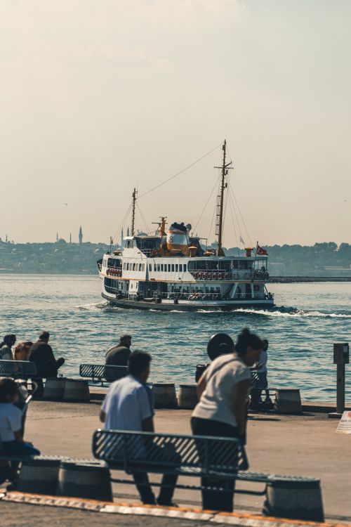 Free Ferry cruising on the Bosphorus with people relaxing by the shore in Istanbul, Turkey. Stock Photo