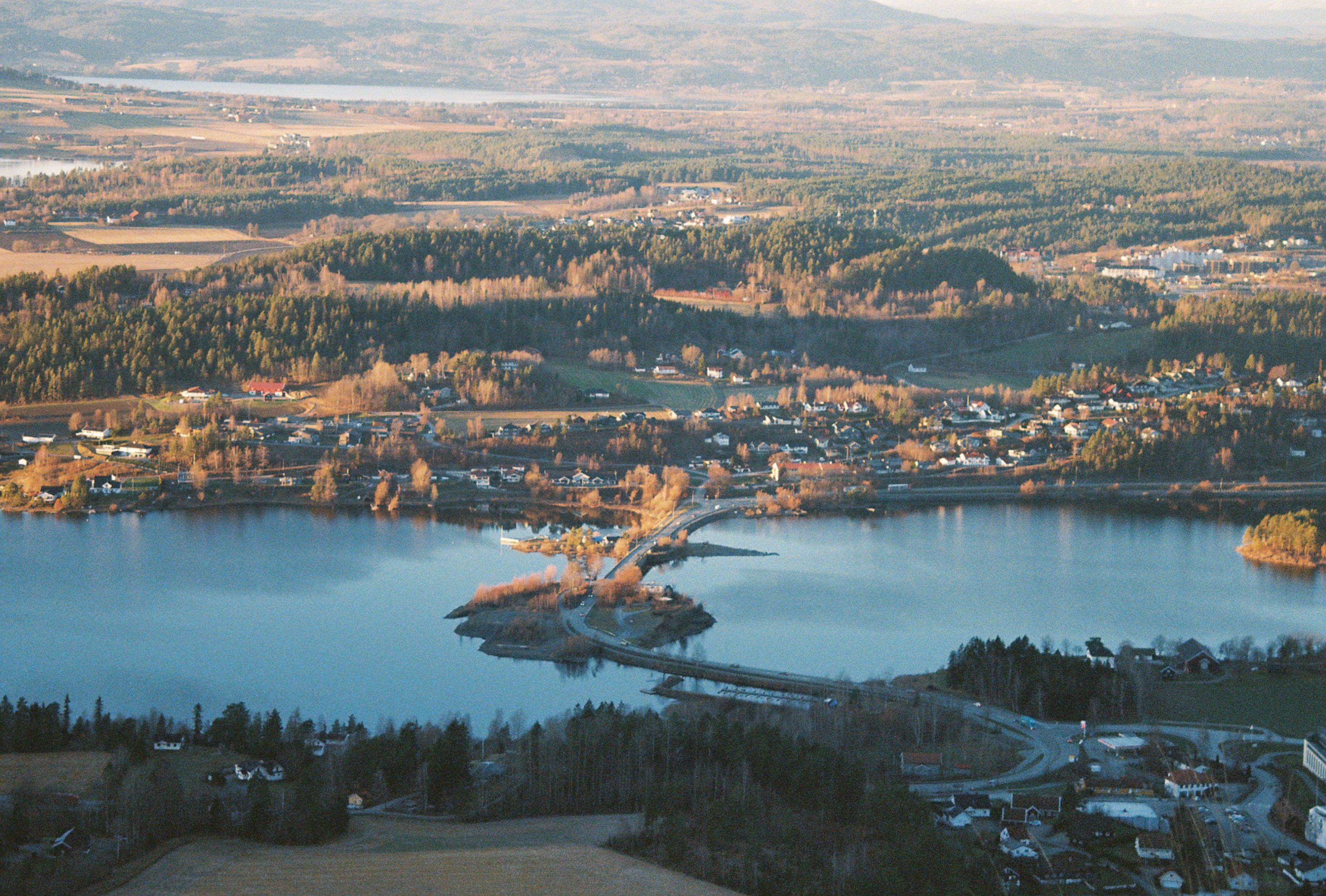 Tranquil aerial view of a serene Norwegian lake and countryside during daylight.
