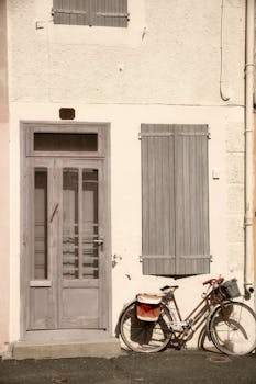 Rustic door and window shutters with a vintage bicycle in a French village setting.