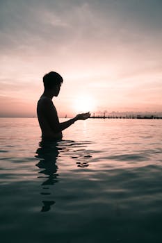 在墨西哥坎昆的浅水中，一名男子捕捉日落时分的平静剪影