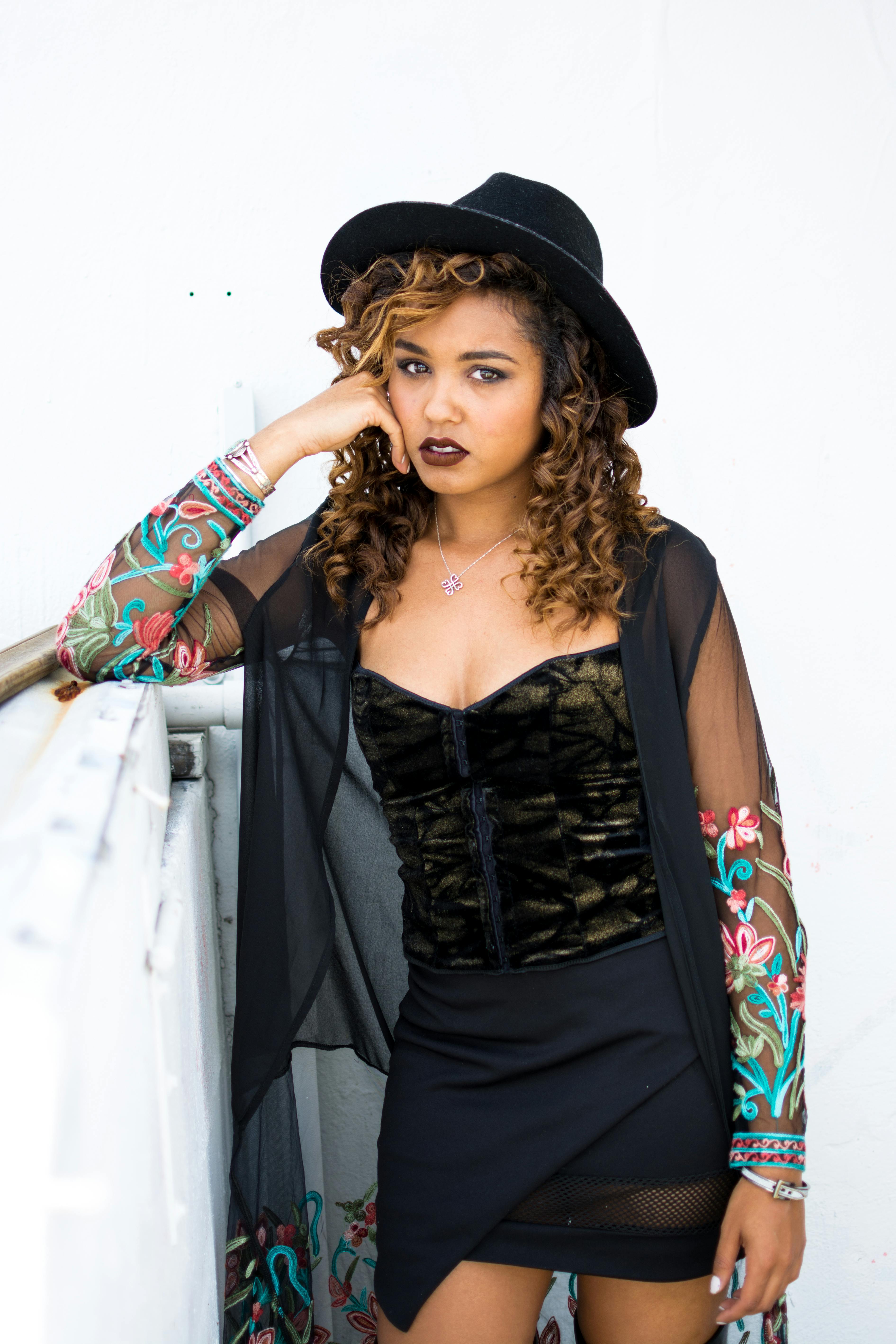 Stylish young woman poses confidently in a fashionable outfit on a white backdrop.