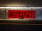 Red-themed New Year mural with bicycle in urban tunnel.