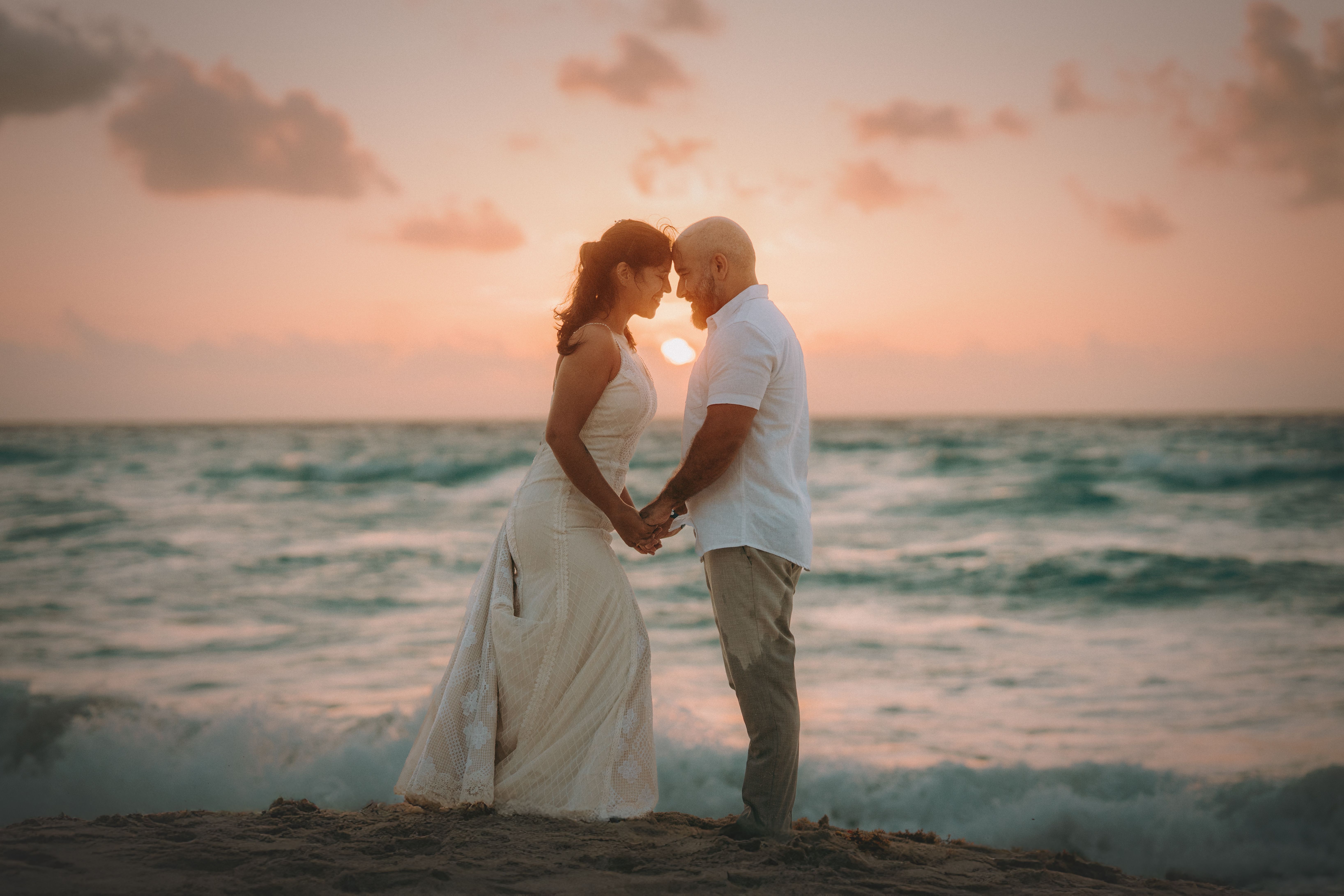A couple embraces at sunset during a beach wedding in Costa Mujeres, Mexico
