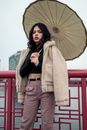 一位手持雨伞的时尚女子在芝加哥的一座桥上摆姿势，展现出现代时尚与自信