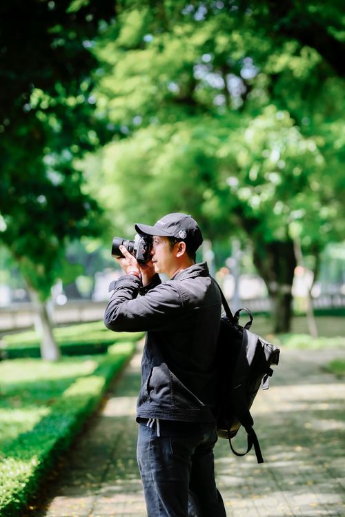 Free Photographer taking photos in a lush green outdoor park setting during the day. Stock Photo