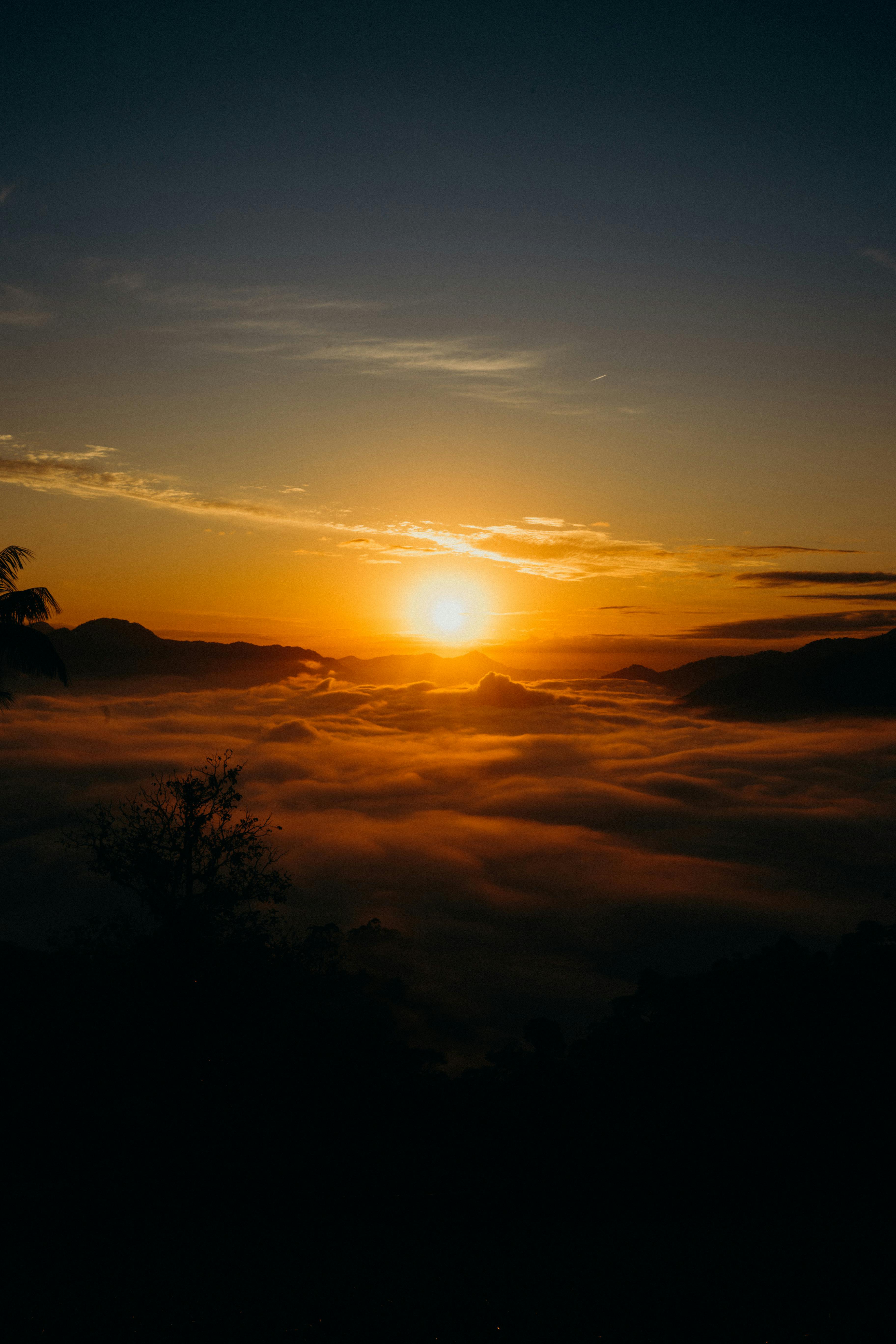 Stunning sunrise with vibrant clouds and silhouette mountains, perfect for nature and travel themes.