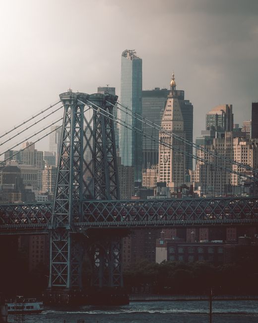 Dramatic view of Manhattan's cityscape featuring the Williamsburg Bridge and towering skyscrapers.