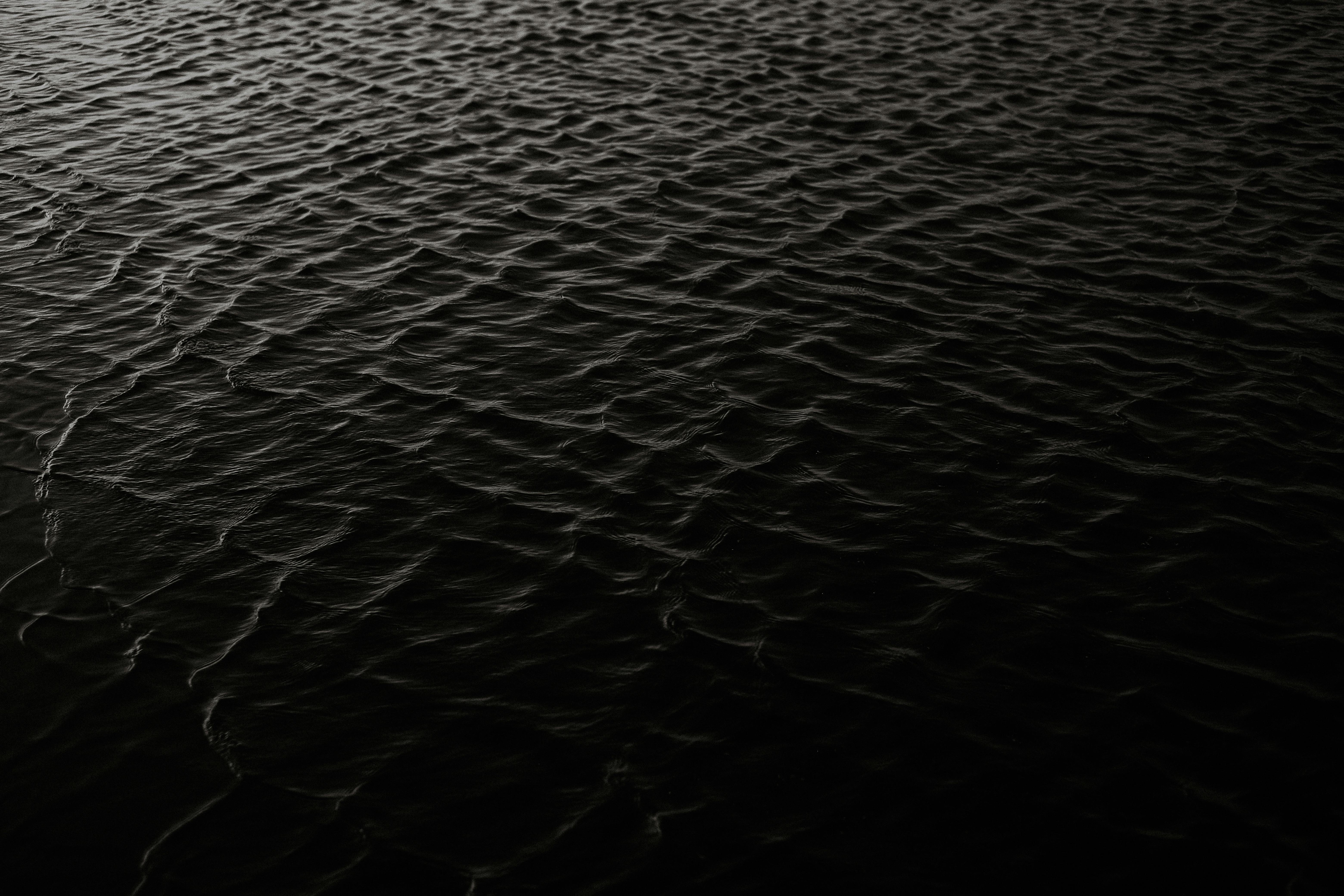 Moody dark ocean with rippling textures and subtle wave patterns.