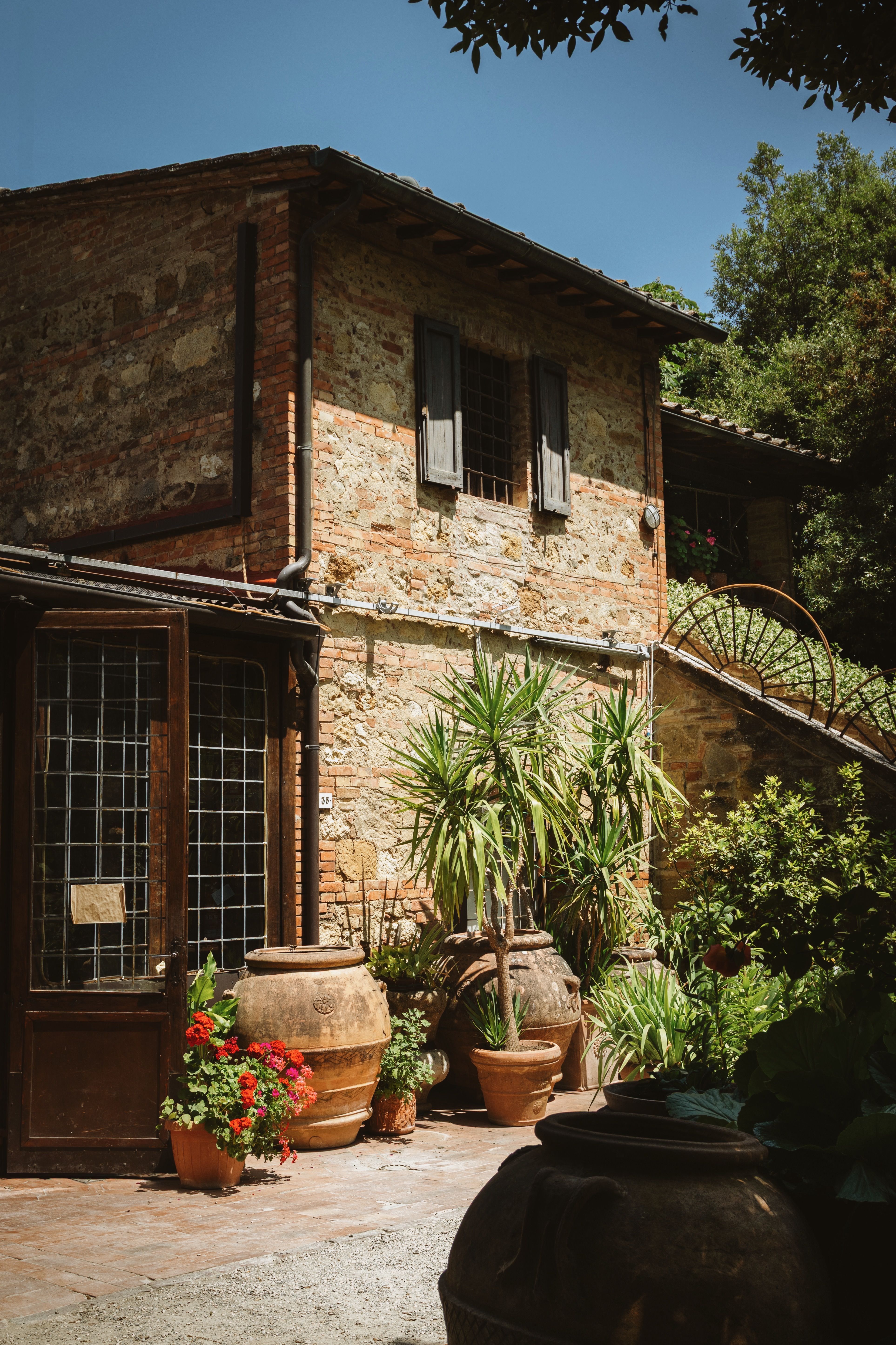 Charming Tuscan villa with vibrant potted plants and rustic architecture, perfect for a serene getaway.