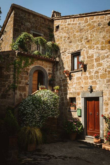 Delightful stone house in Civita di Bagnoregio, Lazio, Italy, adorned with lush greenery and flowers.