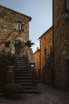 Explore the rustic charm of Civita di Bagnoregio with its stone stairs and historic architecture under a clear sky.