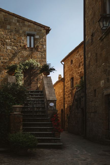 Explore the rustic charm of Civita di Bagnoregio with its stone stairs and historic architecture under a clear sky.