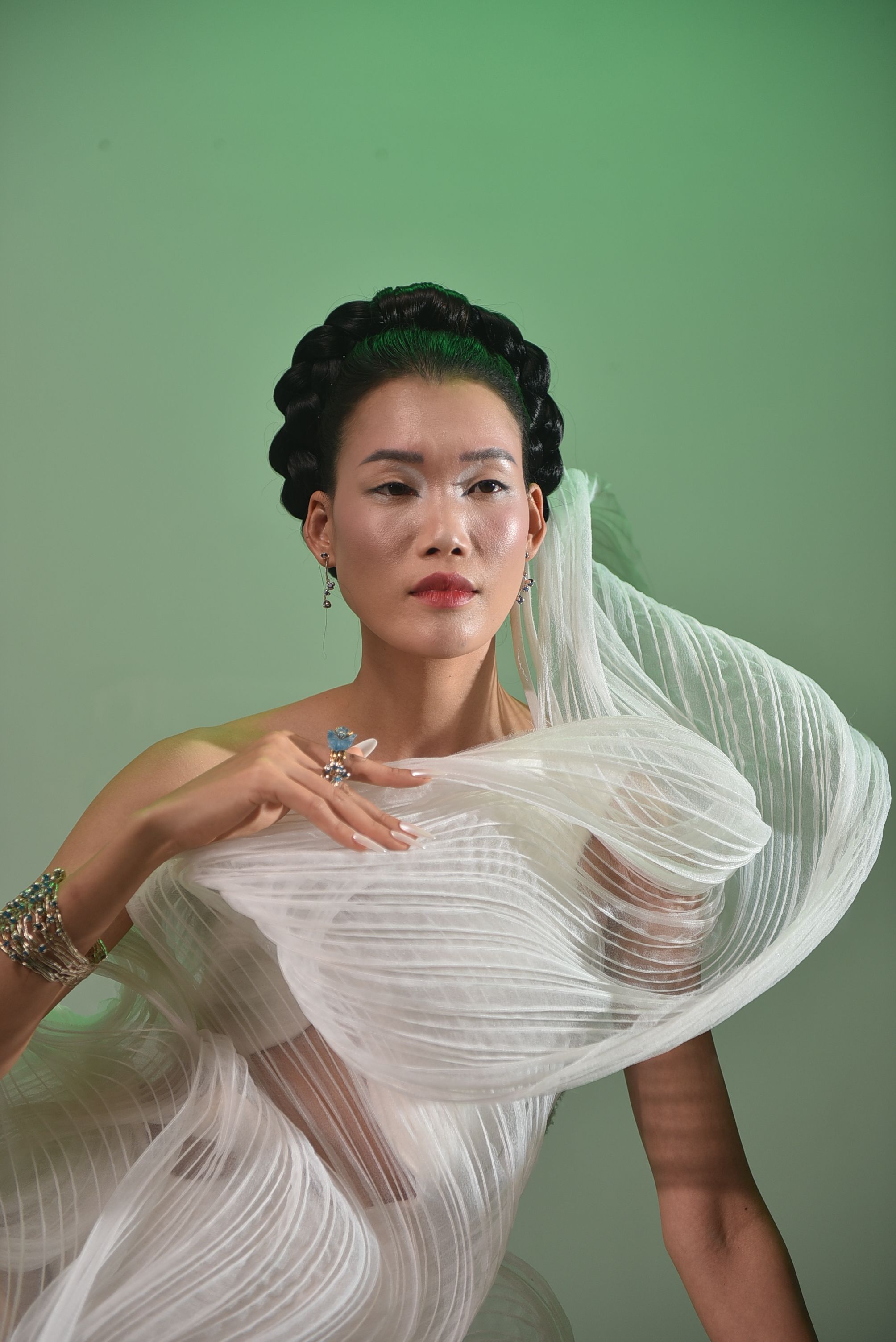 Striking portrait of a woman in an artistic white dress with intricate detailing, exuding modern elegance.