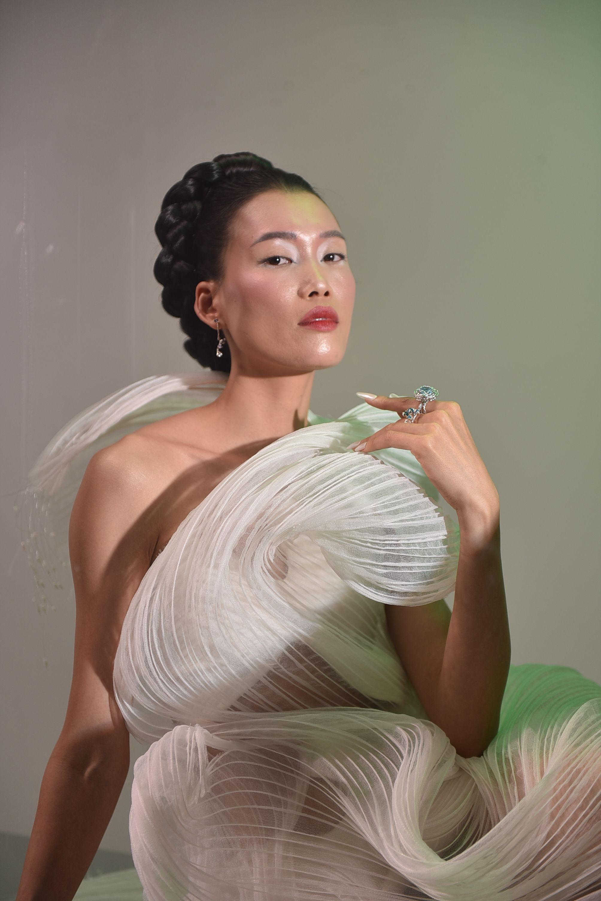 Artistic portrait of a model in an elegant gown with textured draping and soft lighting.