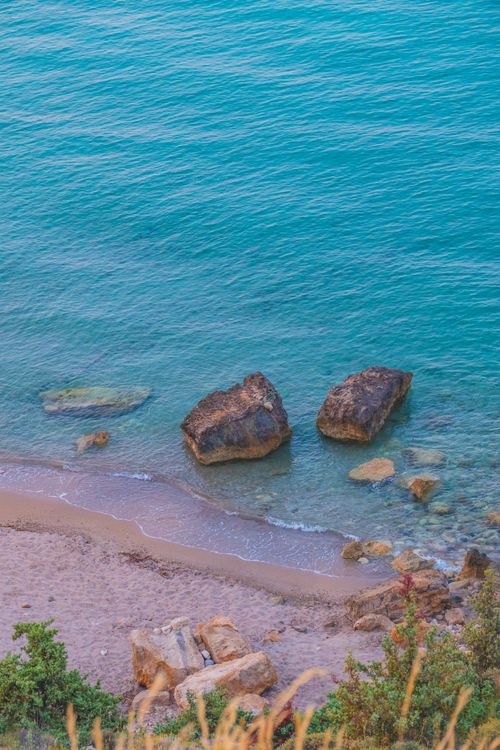 Free Serene coastal view with rocky shoreline and clear turquoise sea, ideal for travel and nature themes. Stock Photo